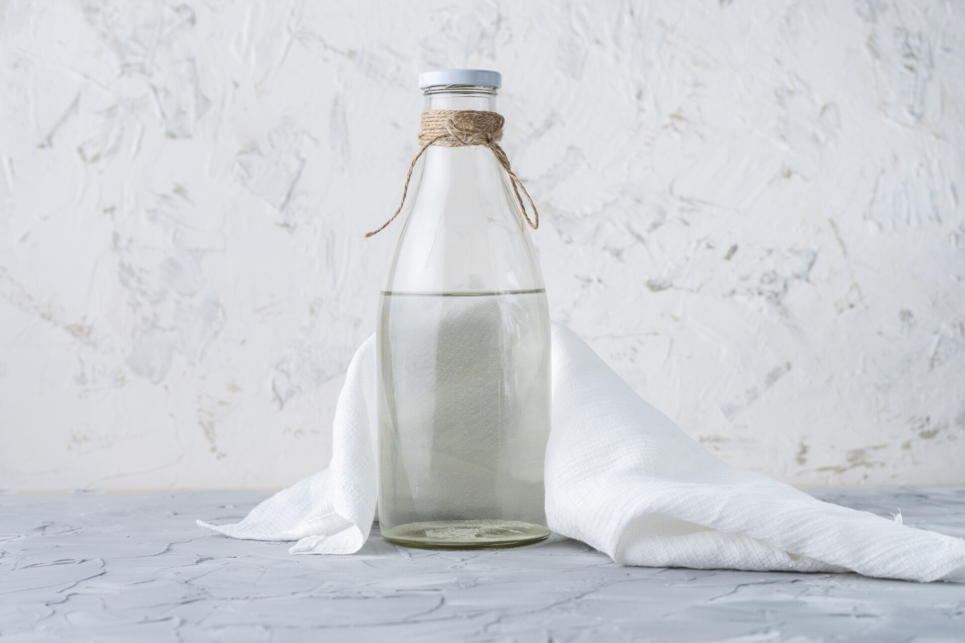 Glazen fles met heldere vloeistof — azijn als huismiddel tegen schimmelnagels