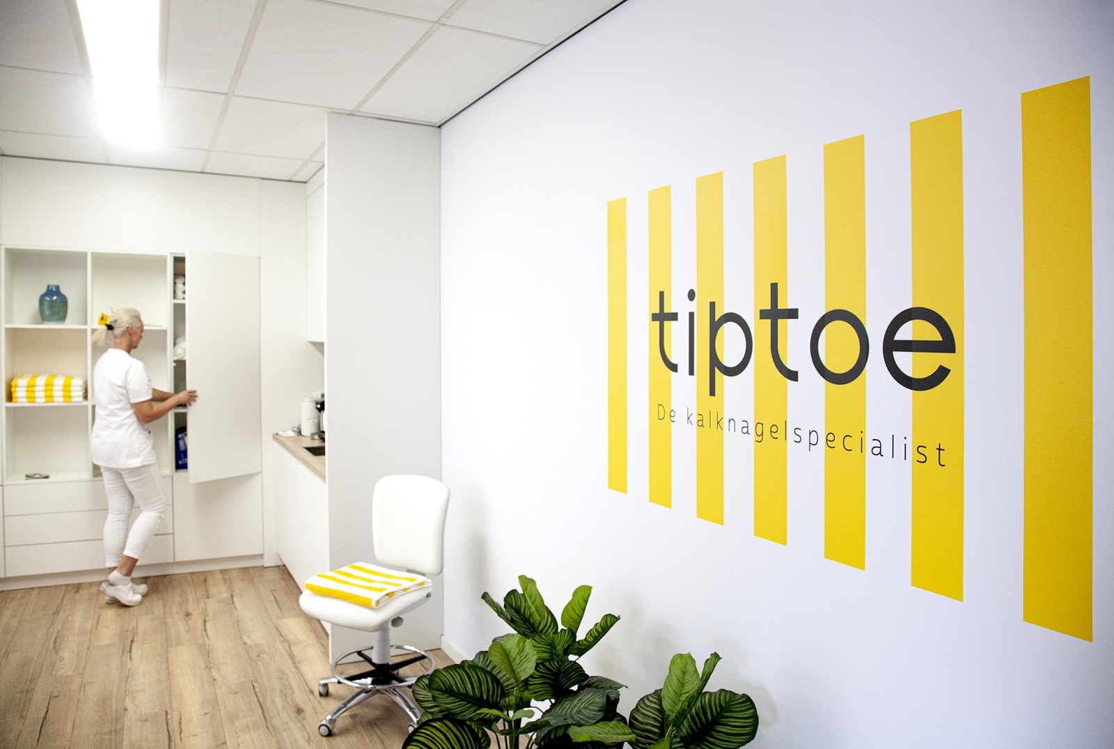 Interieur van een tiptoe salon met een specialist en de tiptoe kalknagelspecialist-logowand
